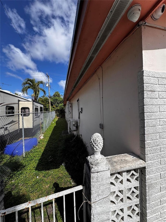 view of side of property featuring a yard, brick siding, and fence