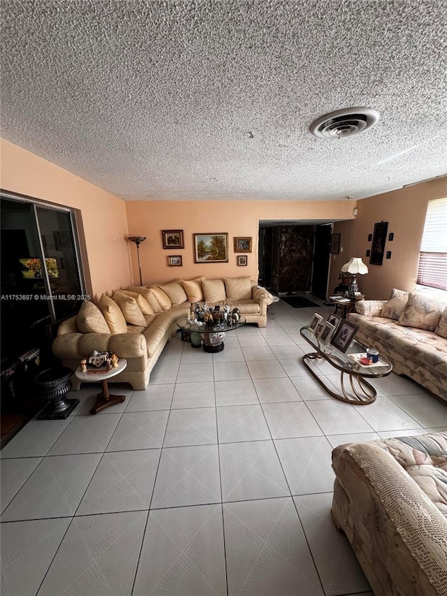 living area with tile patterned flooring, visible vents, and a textured ceiling