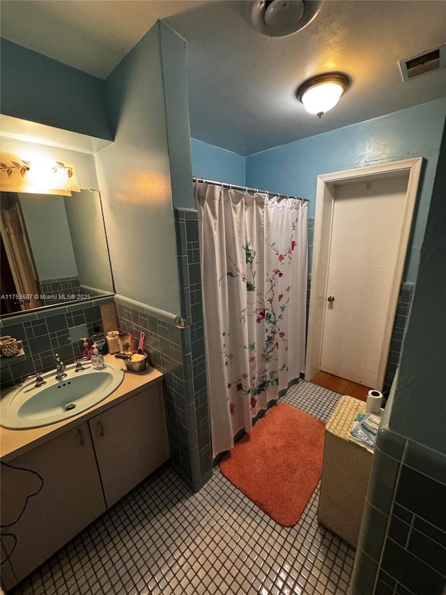 full bathroom with visible vents, vanity, a shower with curtain, tile patterned floors, and tile walls