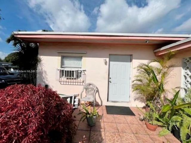 entrance to property with stucco siding and a patio area