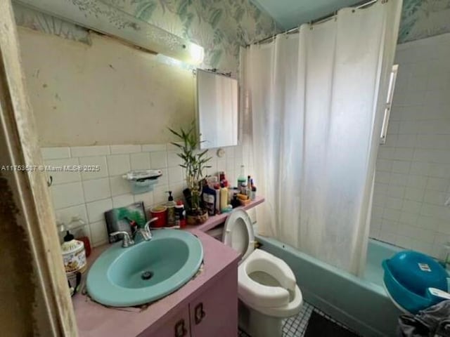 full bath featuring toilet, shower / bath combo, tile walls, wallpapered walls, and vanity