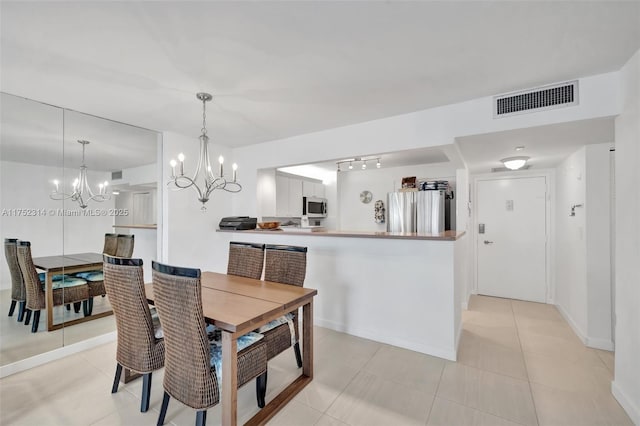 dining area with light tile patterned floors, a notable chandelier, visible vents, and baseboards