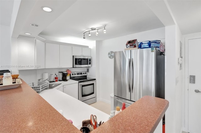 kitchen with recessed lighting, stainless steel appliances, a sink, white cabinetry, and light countertops