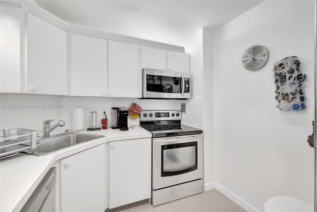 kitchen with white cabinets, stainless steel appliances, a sink, and light countertops