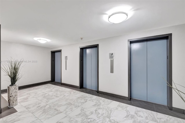 interior space featuring baseboards, marble finish floor, and elevator