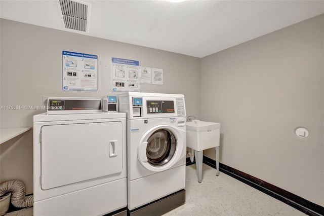 shared laundry area with light floors, washing machine and dryer, visible vents, and baseboards