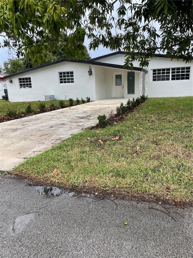 ranch-style house with driveway, a front lawn, an attached carport, and stucco siding