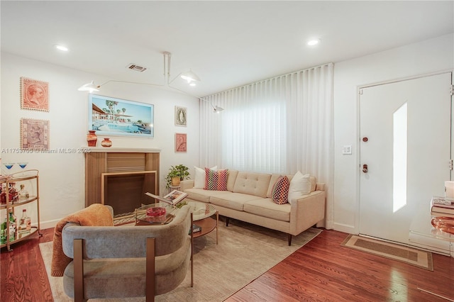 living room featuring a wealth of natural light, a fireplace, visible vents, and wood finished floors