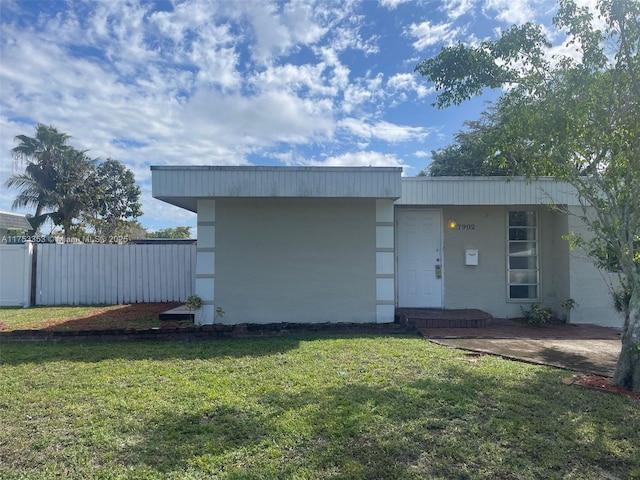 view of front of home with stucco siding, fence, and a front yard