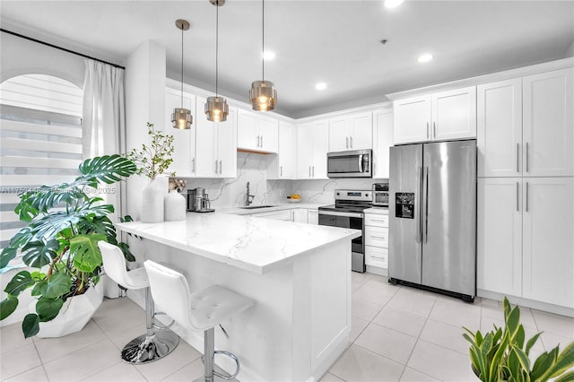 kitchen with tasteful backsplash, appliances with stainless steel finishes, a peninsula, and white cabinetry