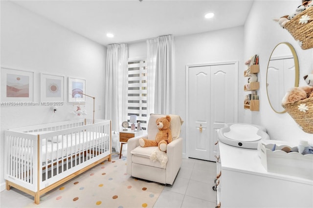 bedroom featuring a nursery area, light tile patterned floors, and recessed lighting