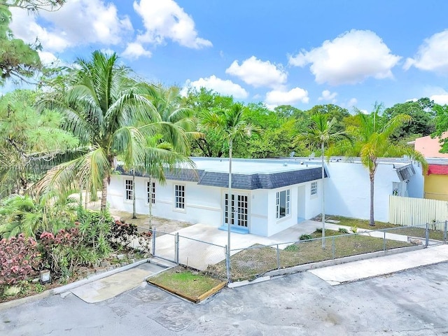 view of front facade with driveway, fence private yard, a gate, french doors, and stucco siding