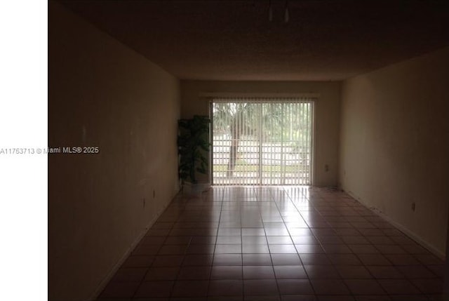 empty room with tile patterned flooring and baseboards