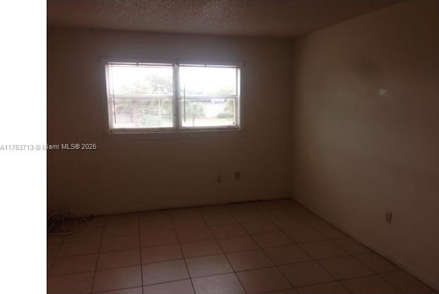 empty room featuring light tile patterned floors and a textured ceiling