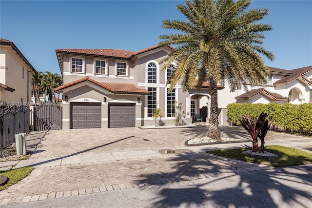 mediterranean / spanish-style home featuring driveway, a garage, a tiled roof, fence, and stucco siding