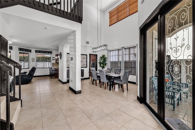 foyer with a towering ceiling, baseboards, and light tile patterned flooring