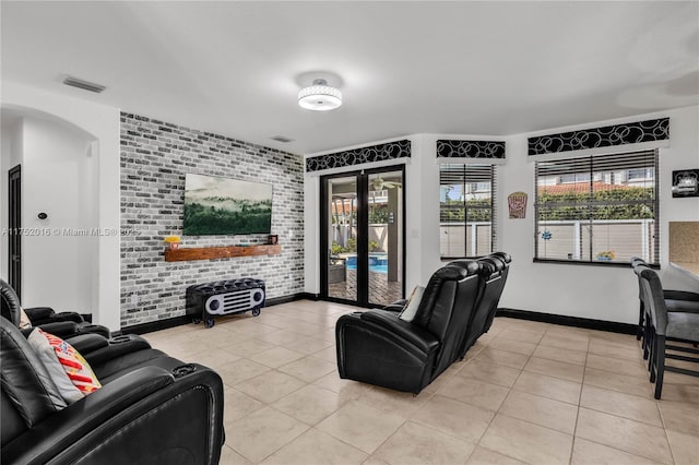 living area featuring brick wall, visible vents, a wealth of natural light, and light tile patterned flooring