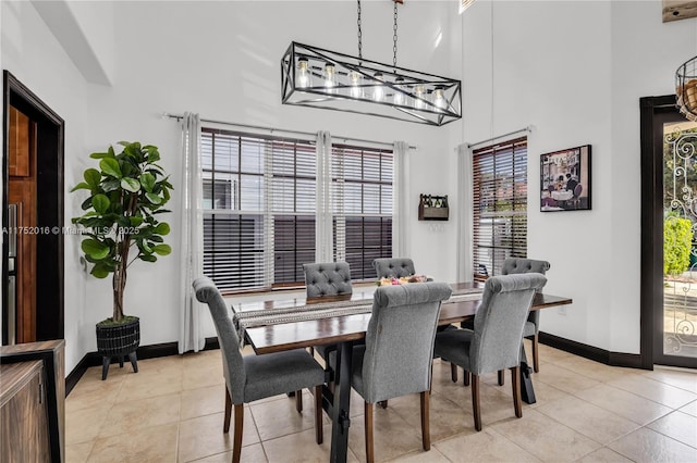 dining space featuring light tile patterned floors, a towering ceiling, and baseboards