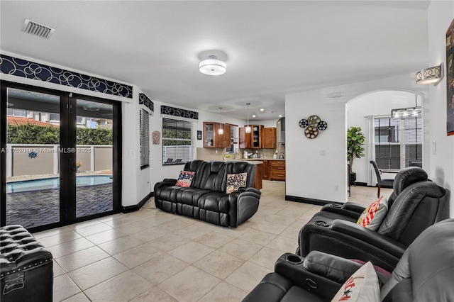 living room with arched walkways, light tile patterned floors, visible vents, baseboards, and french doors