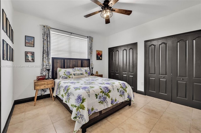 bedroom featuring light tile patterned floors, ceiling fan, baseboards, and two closets