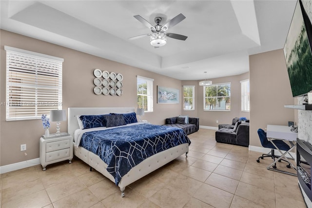 bedroom with light tile patterned flooring, a raised ceiling, a ceiling fan, and baseboards