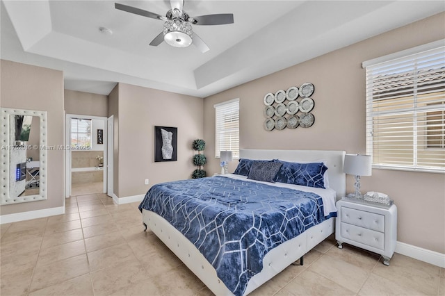 bedroom featuring ensuite bath, baseboards, a raised ceiling, and tile patterned floors