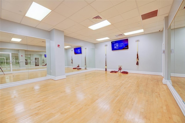 exercise area featuring a drop ceiling, wood finished floors, visible vents, and baseboards