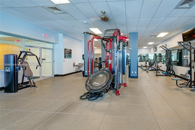 exercise room with visible vents, a paneled ceiling, and baseboards