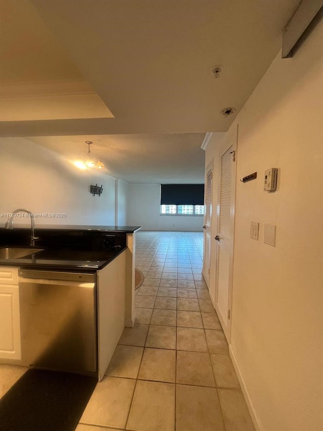 hall featuring light tile patterned floors, baseboards, and a sink