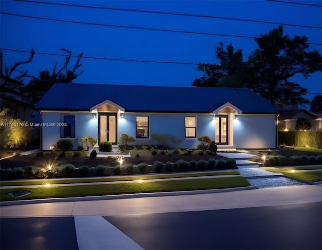 view of front facade featuring stucco siding, metal roof, and french doors