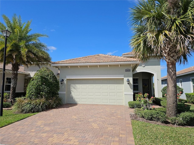 view of front of home with a tiled roof, a garage, decorative driveway, and stucco siding