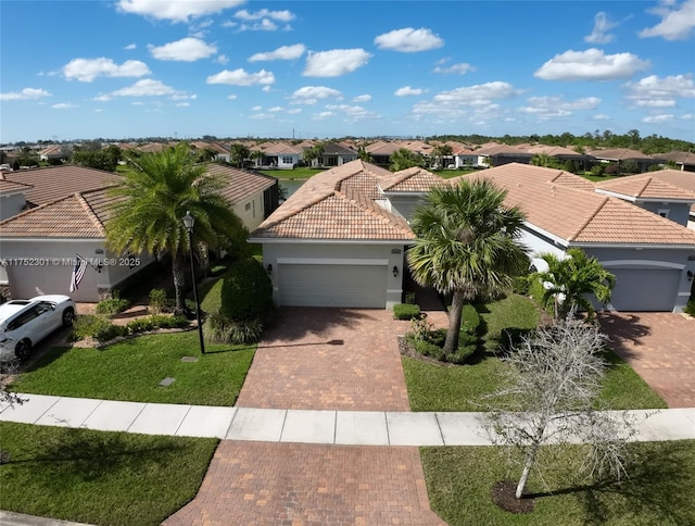 view of front of home featuring stucco siding, a tile roof, decorative driveway, a residential view, and an attached garage