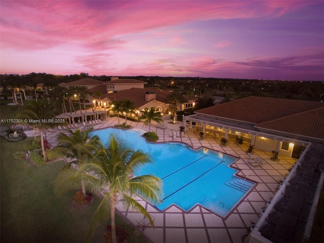 pool at dusk featuring a community pool, fence, and a patio area