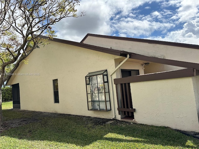 view of side of home with a yard and stucco siding