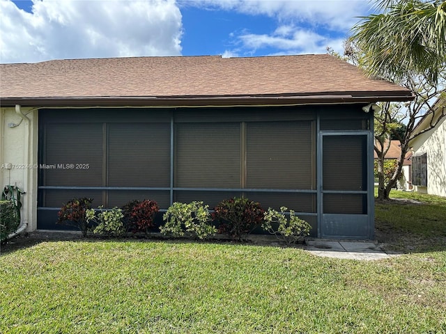 view of home's exterior with a shingled roof, a lawn, and stucco siding