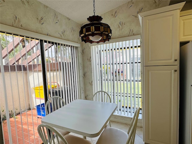 dining area with a textured ceiling, light tile patterned floors, and wallpapered walls