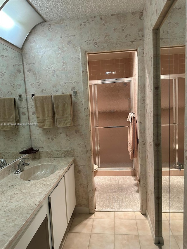 full bathroom with a textured ceiling, tile patterned flooring, vanity, a stall shower, and wallpapered walls