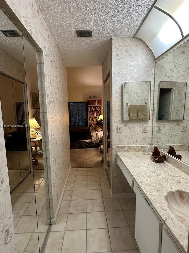 ensuite bathroom with tile patterned floors, vanity, a textured ceiling, and ensuite bathroom