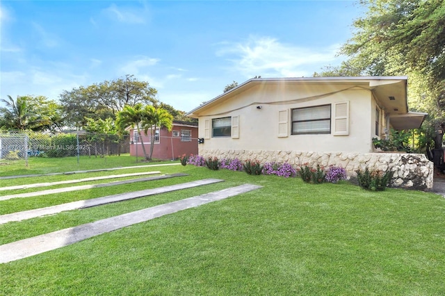 exterior space featuring an outbuilding, stucco siding, a lawn, and fence