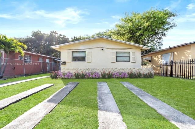 bungalow-style house featuring a front yard, fence, and stucco siding