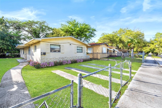 view of home's exterior with a fenced front yard, a gate, a yard, and stucco siding