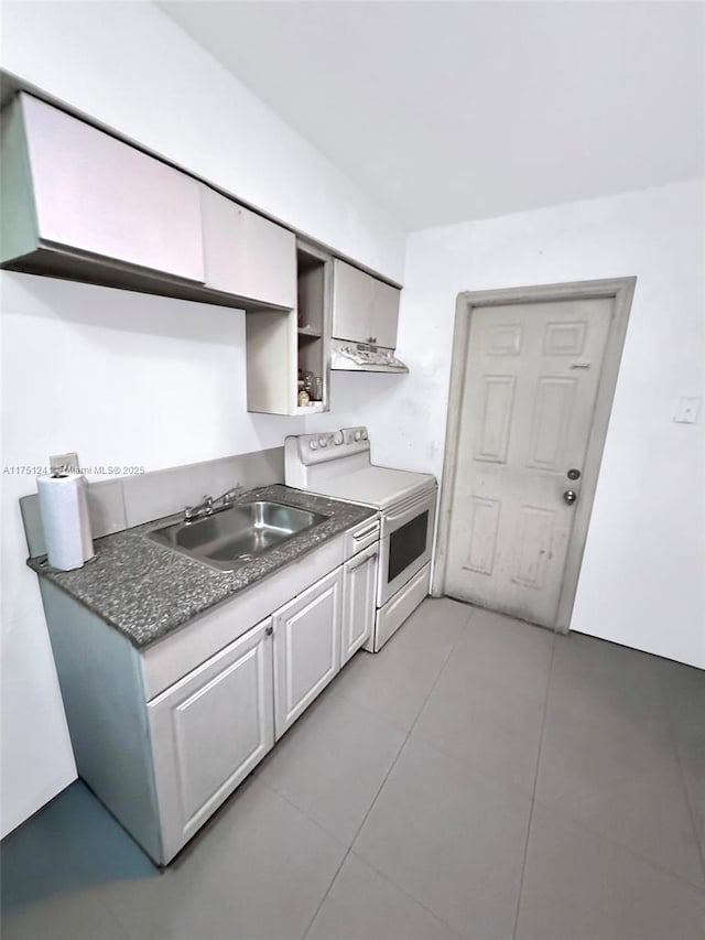 kitchen with dark countertops, white range with electric cooktop, a sink, and light tile patterned flooring