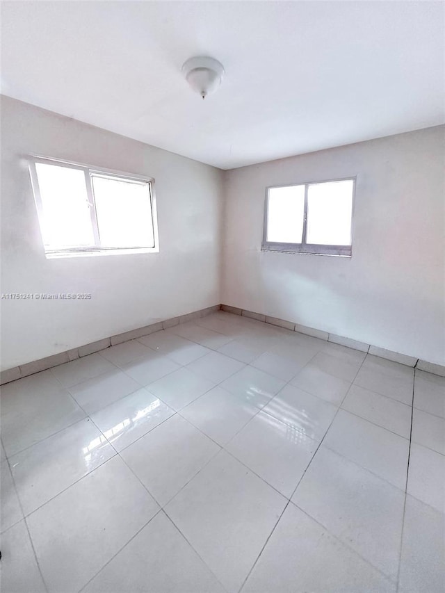 empty room featuring baseboards and light tile patterned floors