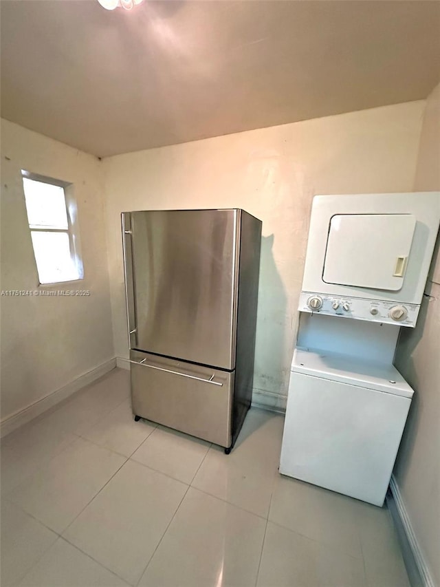 kitchen featuring stacked washer and dryer, freestanding refrigerator, baseboards, and light tile patterned floors