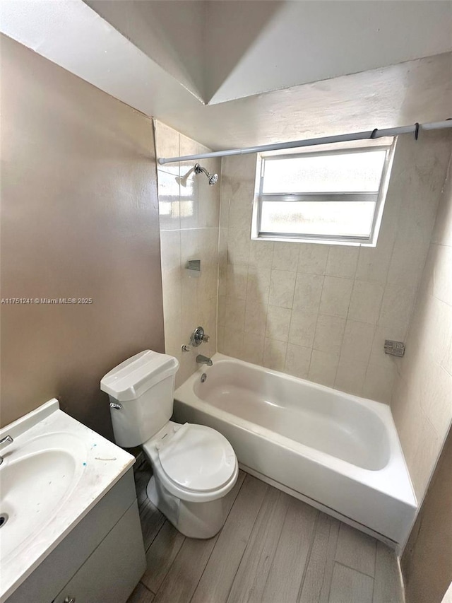 bathroom featuring toilet, vanity, shower / bathtub combination, and wood finished floors