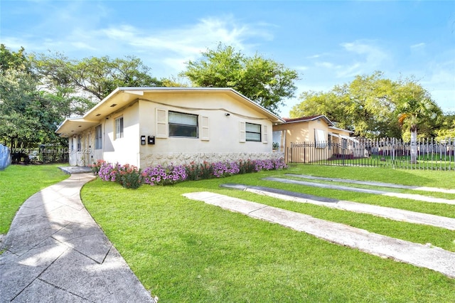 bungalow-style home with fence private yard, a front lawn, and stucco siding