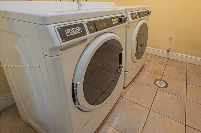 laundry area with washer and clothes dryer, light tile patterned flooring, and baseboards
