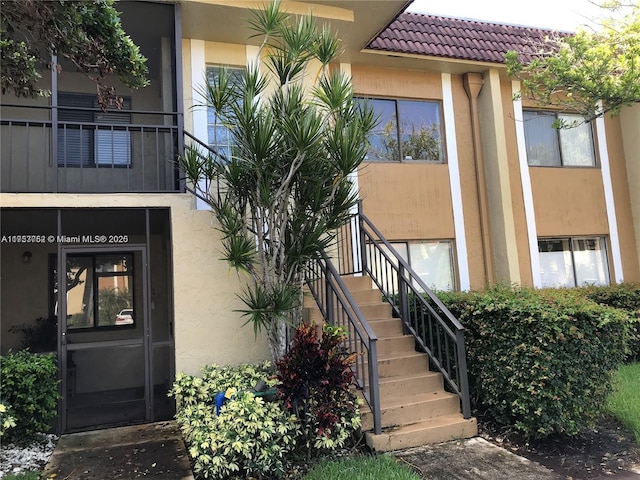 view of exterior entry with a tiled roof and stucco siding