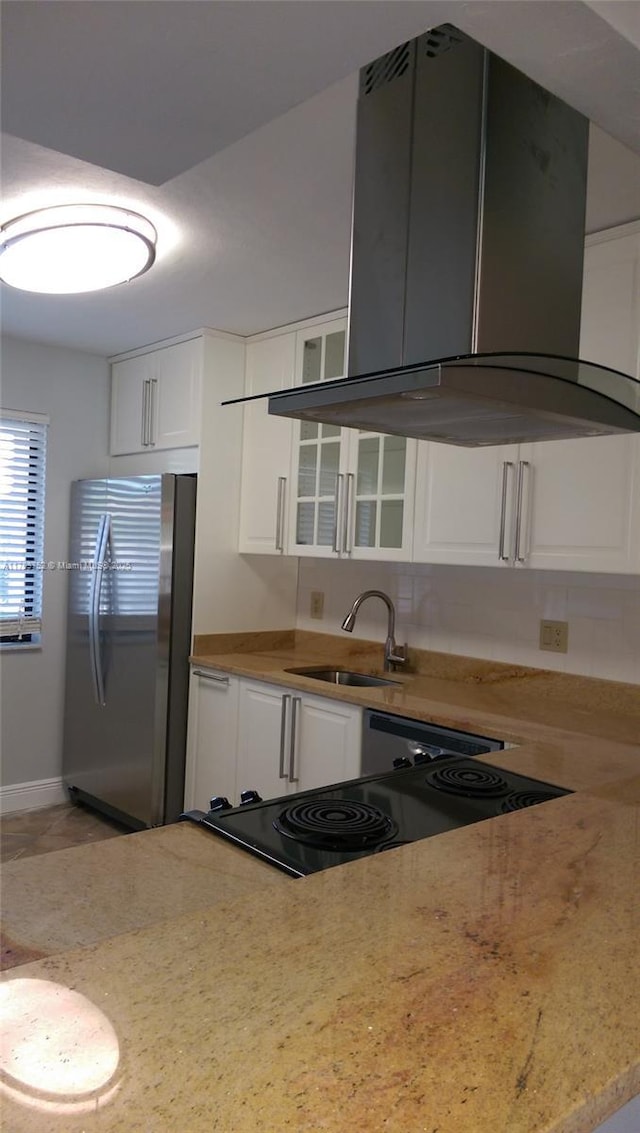 kitchen with freestanding refrigerator, white cabinetry, island exhaust hood, and a sink