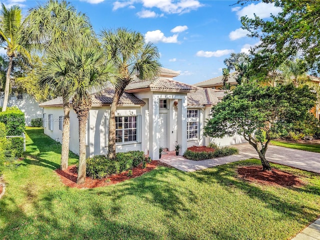 mediterranean / spanish-style house featuring a garage, a tile roof, driveway, stucco siding, and a front lawn